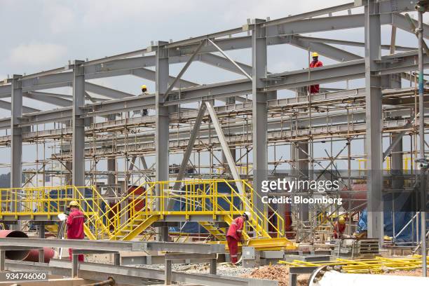 Surveyor, left, works at the under construction Petronas Nasional Berhad Refinery and Petrochemical Integrated Development Project, part of the...