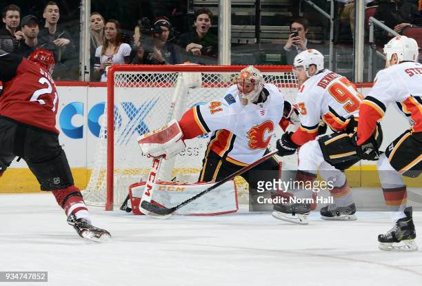 Goalie Mike Smith of the Calgary Flames looks to make a save as Derek Stepan of the Arizona Coyotes skates in with the puck during the first period...