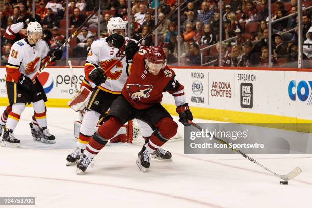 Arizona Coyotes right wing Christian Fischer tries to control the puck defended by Calgary Flames center Sean Monahan during the NHL hockey game...