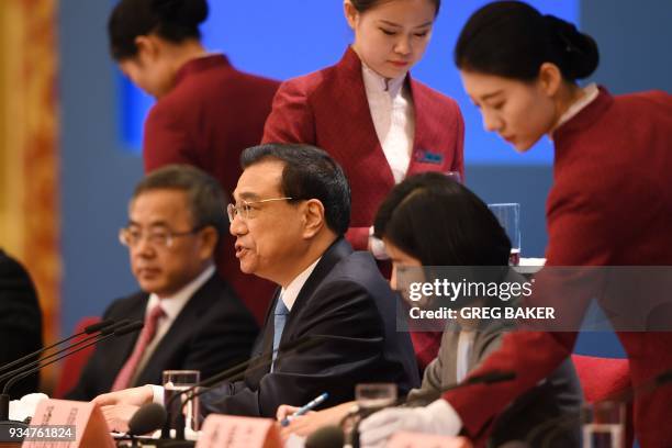 China's Premier Li Keqiang speaks as attendants top up his glass during a press conference after the closing session of the National People's...
