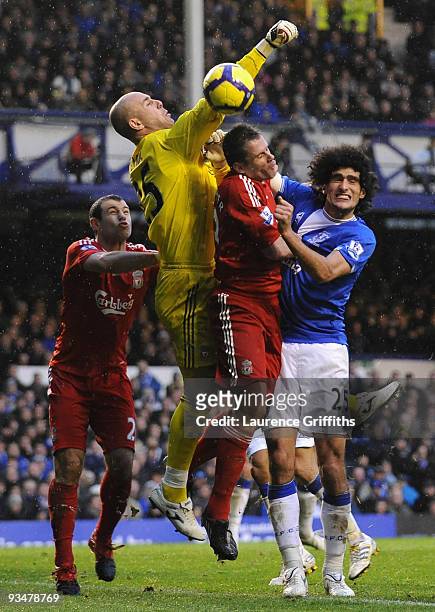 Pepe Reina of Liverpool punches clear under pressure from Marouane Fellaini of Everton during the Barclays Premier League match between Everton and...