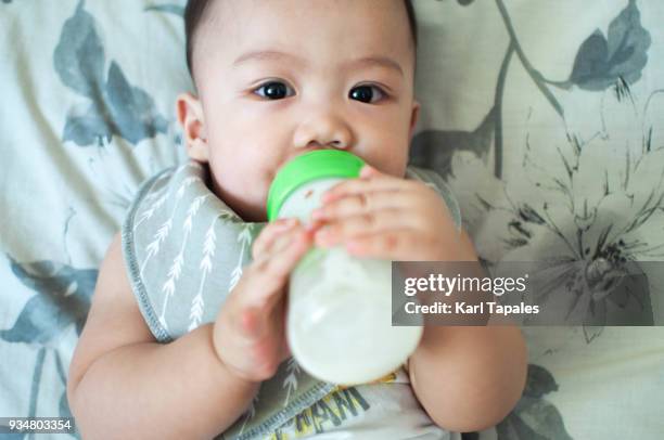 a baby boy is feeding on formula milk - milk pumping stockfoto's en -beelden