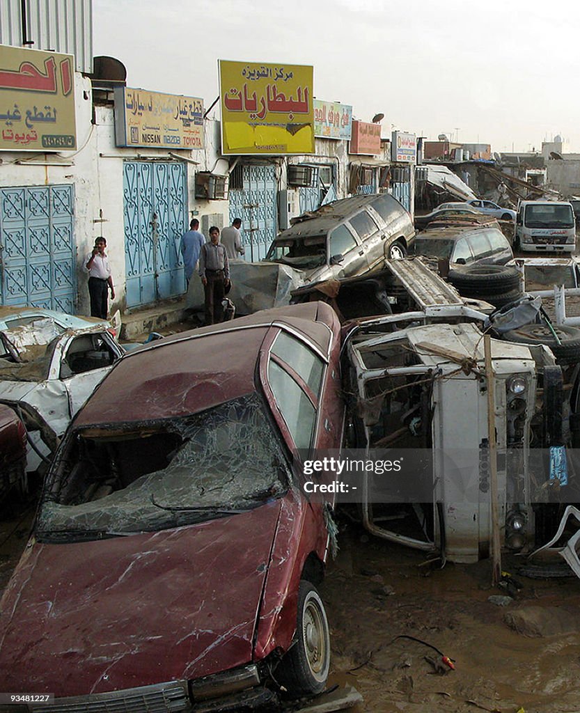 People walk past a pile of cars in the S
