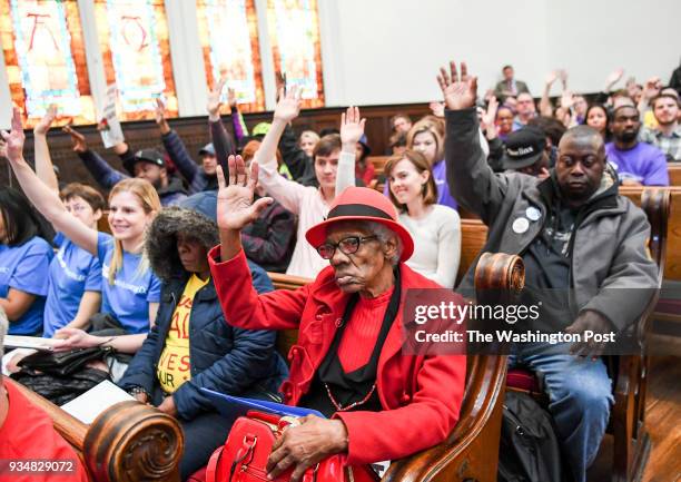 Resident, Cecelia Thompson raises her hand with the crowd when they are asked who wants and needs affordable housing at the More For Housing Now...