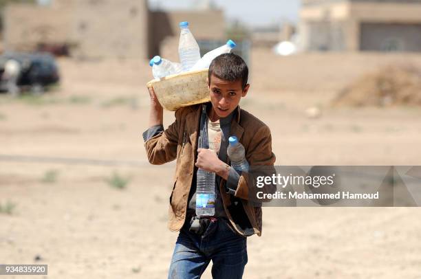 Yemeni child returns home with jerrycans after he filled it with water on March 18, 2018 in Sana'a, Yemen.