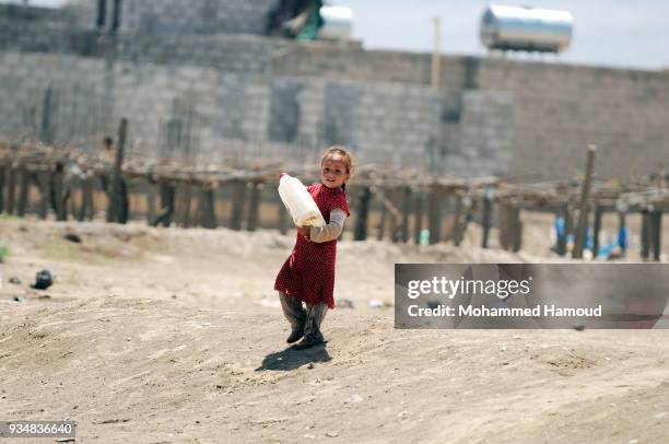 Little Yemeni girl carries a jerrycan returns home after she filled it with water on March 18, 2018 in Sana'a, Yemen.