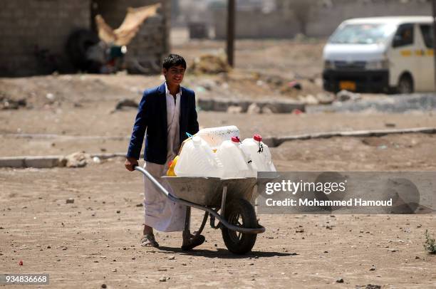 Yemeni young pushes a wheelbarrow carries jerrycans to fill it with water on March 18, 2018 in Sana'a, Yemen.