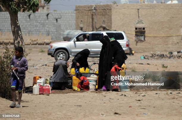Yemeni people fill their jerrycans with water on March 18, 2018 in Sana'a, Yemen.