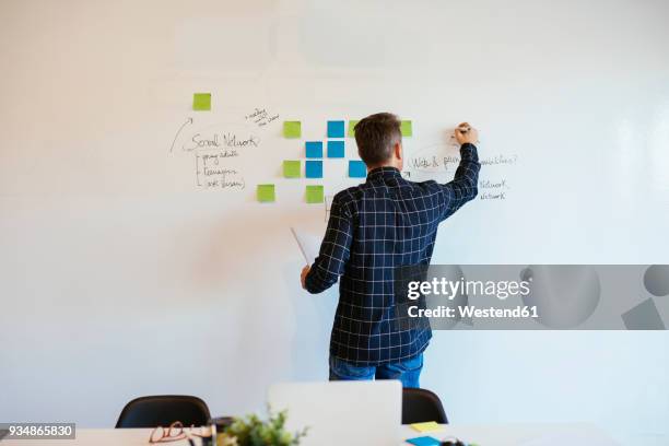 businessman in office writing on whiteboard - whiteboard stock pictures, royalty-free photos & images