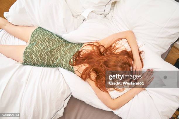 back view of redheaded woman lying on bed - auf dem bauch liegen stock-fotos und bilder
