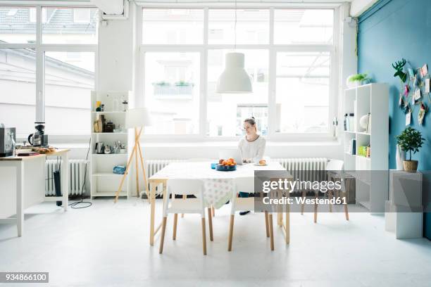smiling woman working on laptop in a loft - bright white people stock pictures, royalty-free photos & images
