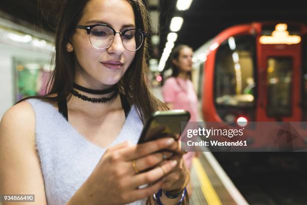 teenage girl using cell phone at subway station - tube girl fotografías e imágenes de stock