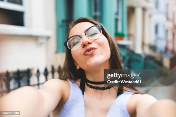 happy teenage girl in the city taking a selfie - kussmund stock-fotos und bilder