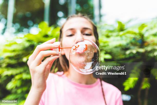 young woman blowing soap bubbles outdoors - bubble ring stock pictures, royalty-free photos & images