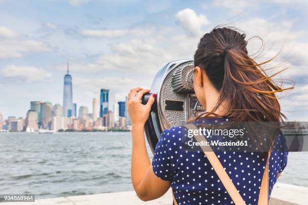 usa, new york, woman looking at manhattan skyline with coin-operated binoculars - new york tourist stockfoto's en -beelden