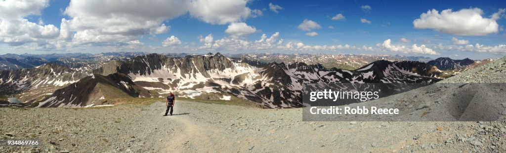 A person walking alone on a high, remote mountain trail