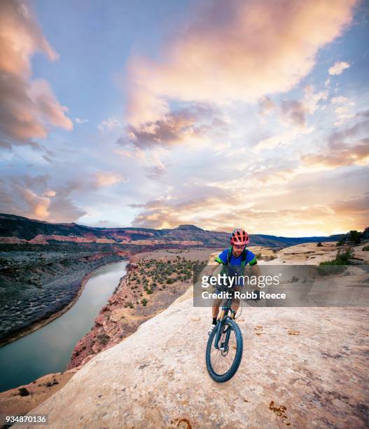 a man riding a mountain bike on an extreme sandstone ledge - robb reece fotografías e imágenes de stock