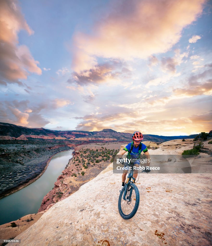 A man riding a mountain bike on an extreme sandstone ledge