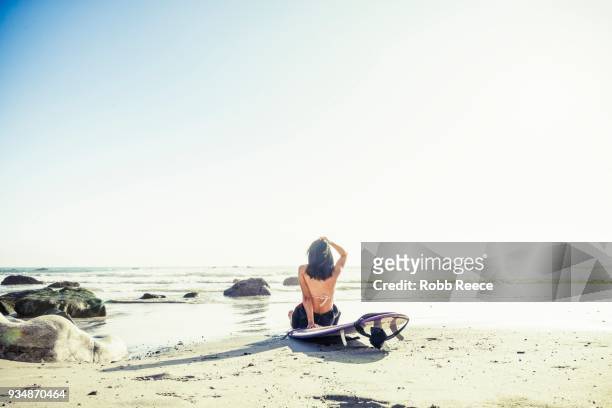 a woman surfer with a surfboard on a remote ocean beach - robb reece stock-fotos und bilder