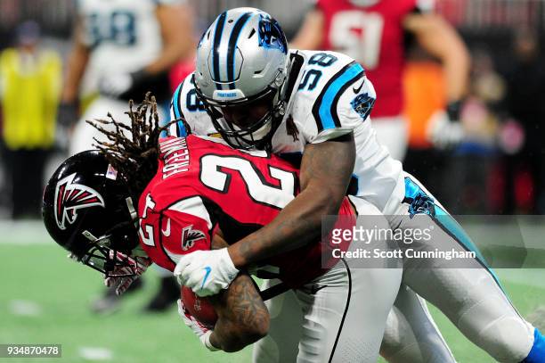 Thomas Davis of the Carolina Panthers tackles Devonta Freeman of the Atlanta Falcons during the first half at Mercedes-Benz Stadium on December 31,...