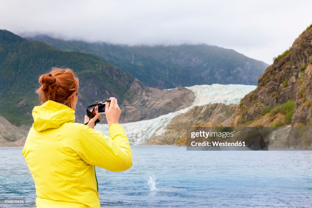 USA, Alaska, Juneau, female tourist photographing Mendenhall Glacier