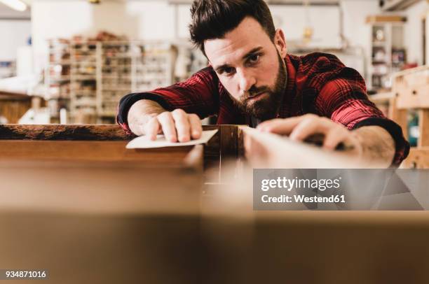 man treating wood in workshop with sand paper - präzision stock-fotos und bilder