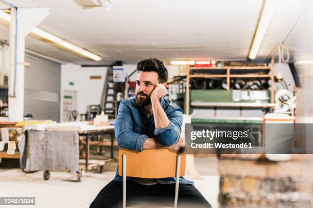 man sitting on chair in workshop - pessimism stock pictures, royalty-free photos & images