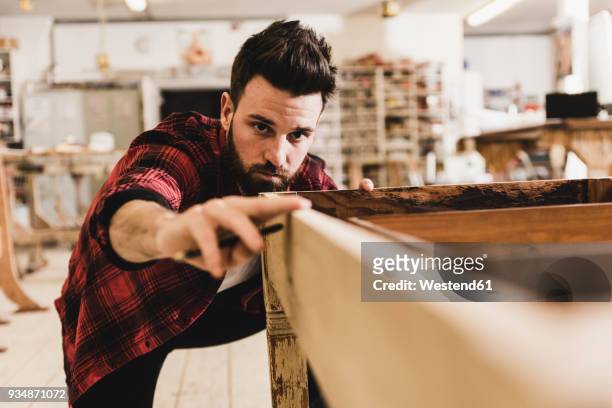 man examining wood in workshop - craft stock-fotos und bilder
