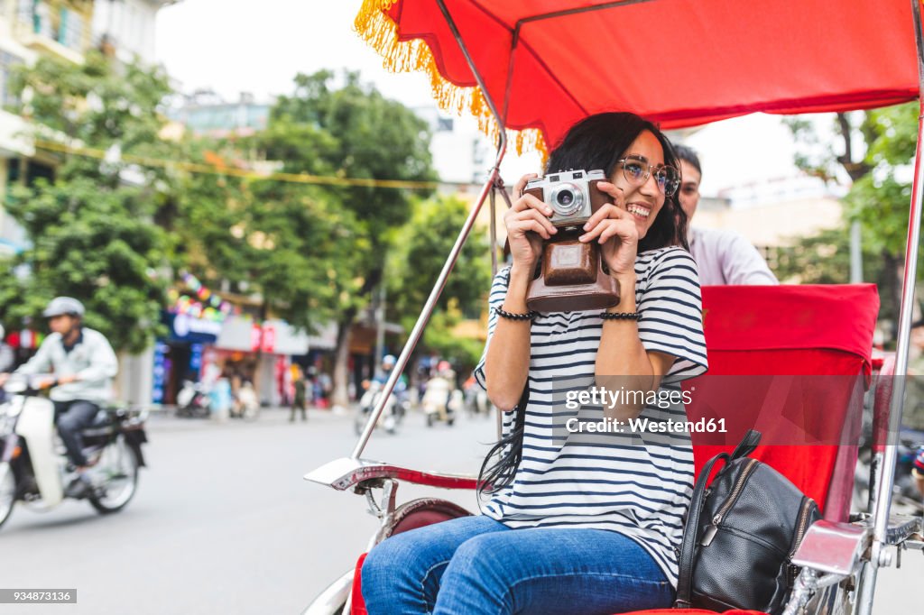 Vietnam, Hanoi, young woman with old-fashioned camera on a riksha