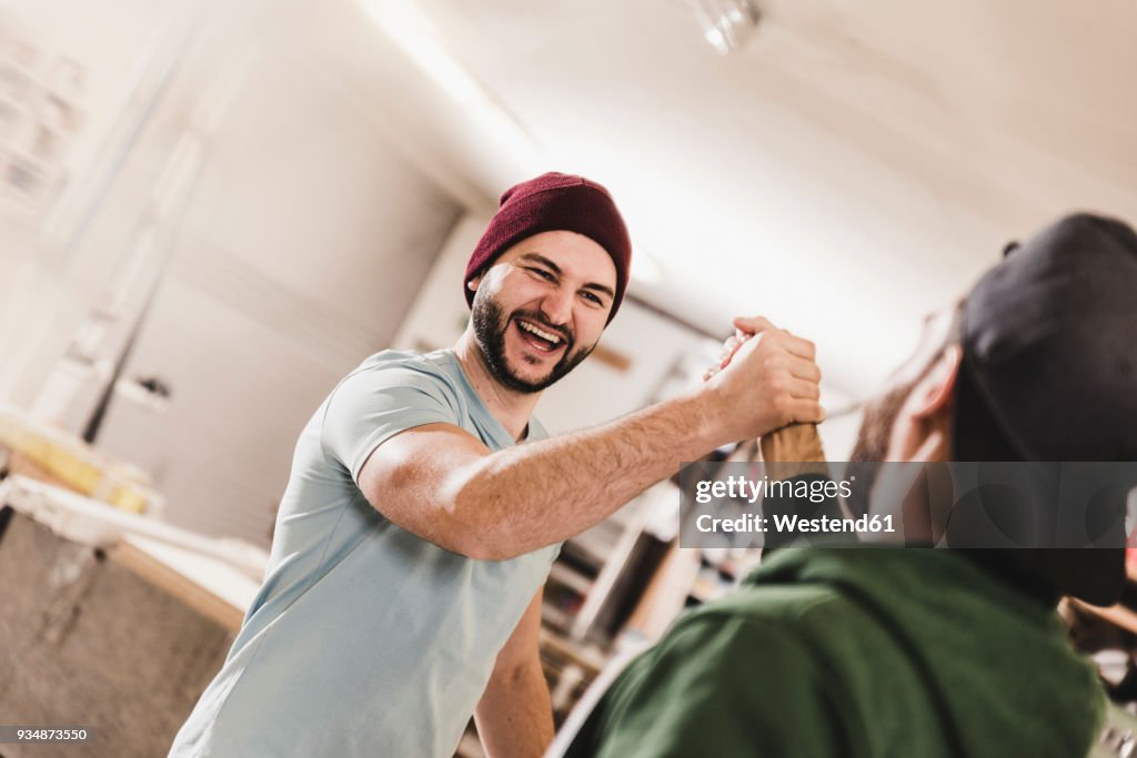 Two happy young men high fiving in workshop