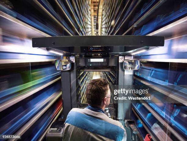 worker operating high rack in storehouse - modern warehouse stock pictures, royalty-free photos & images