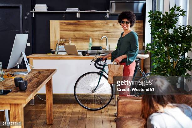 Young woman with bicycle arriving in modern office