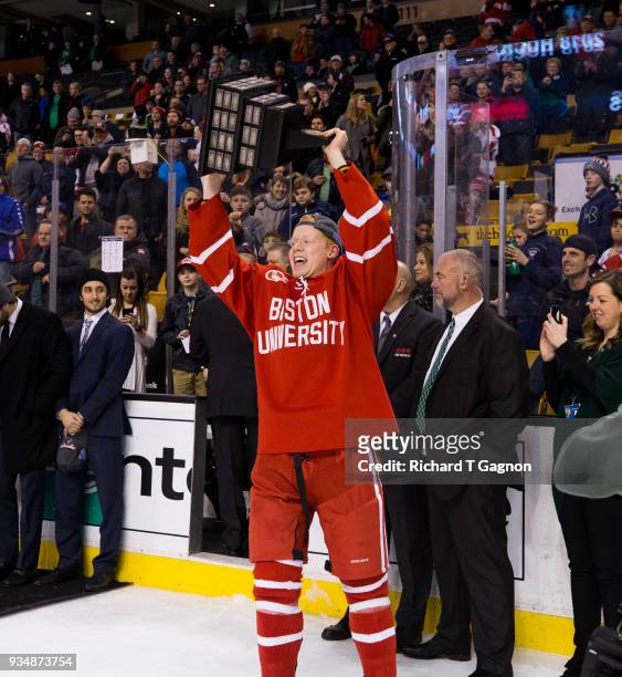 Chase Phelps of the Boston University Terriers raises the Lamorillo Trophy after a game against the Providence College Friars during NCAA hockey in...