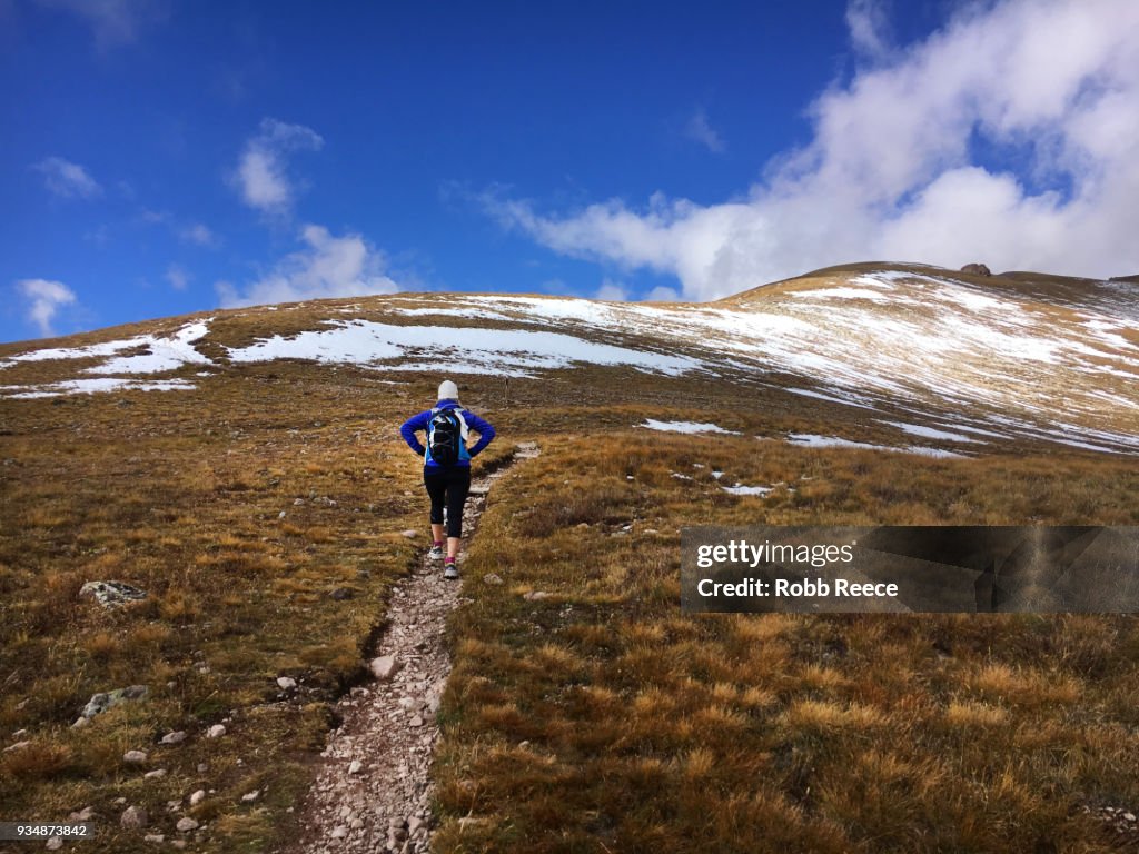A woman hiking uphill on a remote mountain trail
