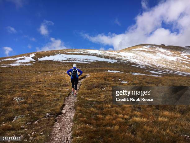 a woman hiking uphill on a remote mountain trail - robb reece imagens e fotografias de stock