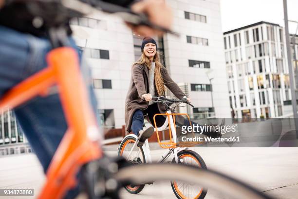 carefree woman with man riding bicycle in the city - radfahren stock-fotos und bilder