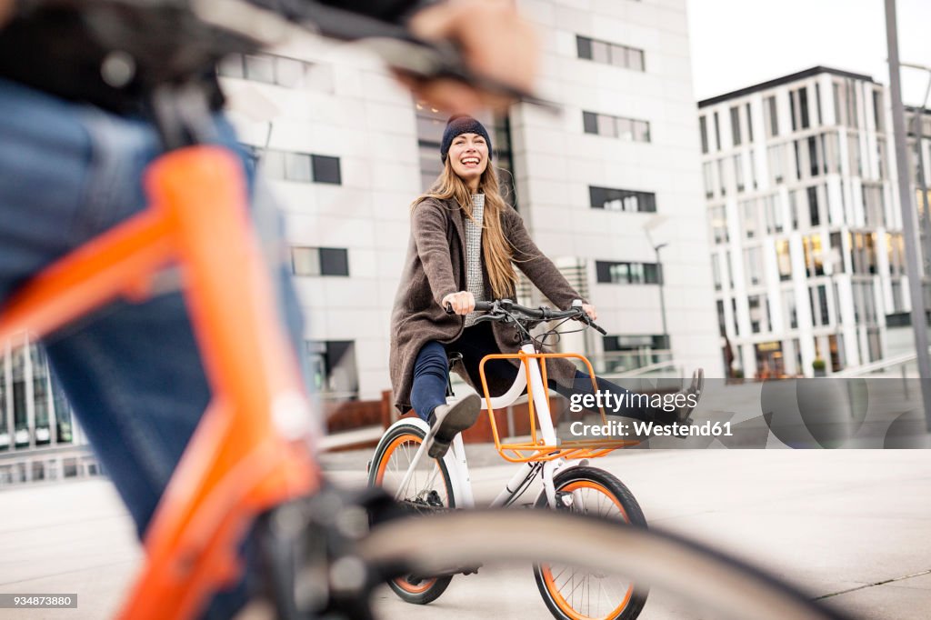 Carefree woman with man riding bicycle in the city