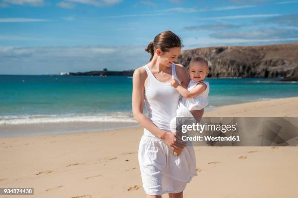 mother holding little daughter on the beach - baby lachen natur stock-fotos und bilder