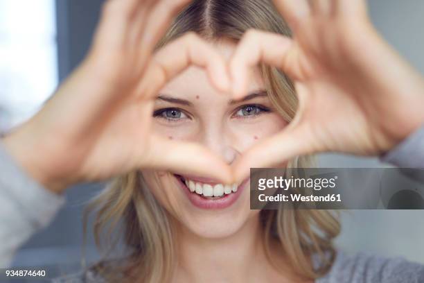 portrait of laughing woman building heart with her fingers - admiration stock pictures, royalty-free photos & images