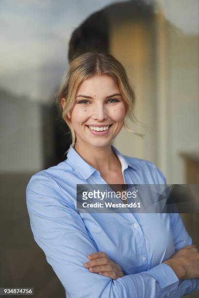portrait of content businesswoman behind windowpane - business woman blue stock-fotos und bilder