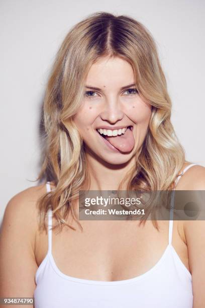 portrait of blond woman sticking out tongue - stick tongue out stock pictures, royalty-free photos & images