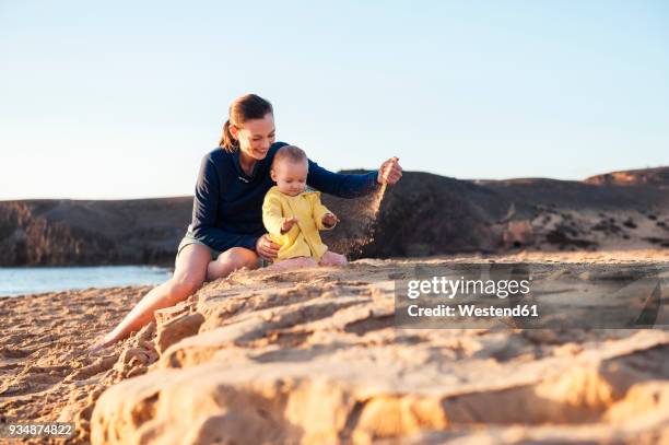 mother playing with little daughter on the beach - één ouder stockfoto's en -beelden