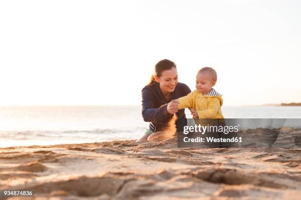 mother playing with little daughter on the beach - één ouder stockfoto's en -beelden