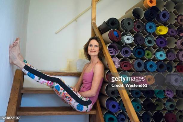 relaxed mature woman on stairs next to assortment of yoga mats - large group of objects sport stock pictures, royalty-free photos & images
