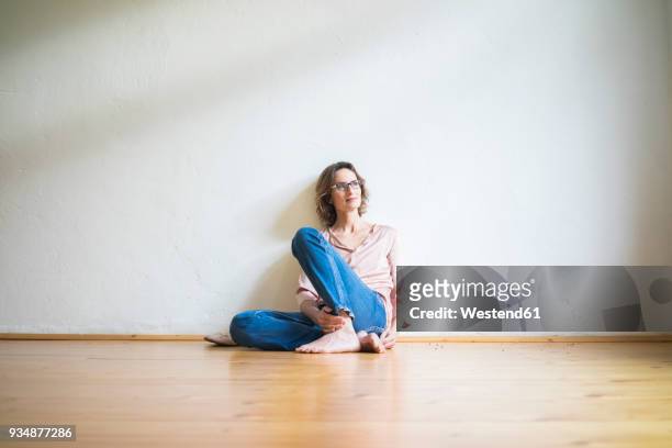 mature woman sitting on floor in empty room thinking - women wearing nothing stock pictures, royalty-free photos & images