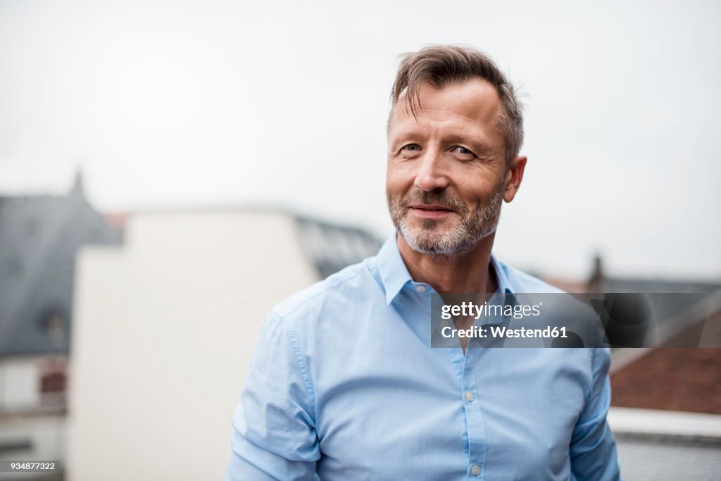Portrait of smiling mature businessman on roof terrace