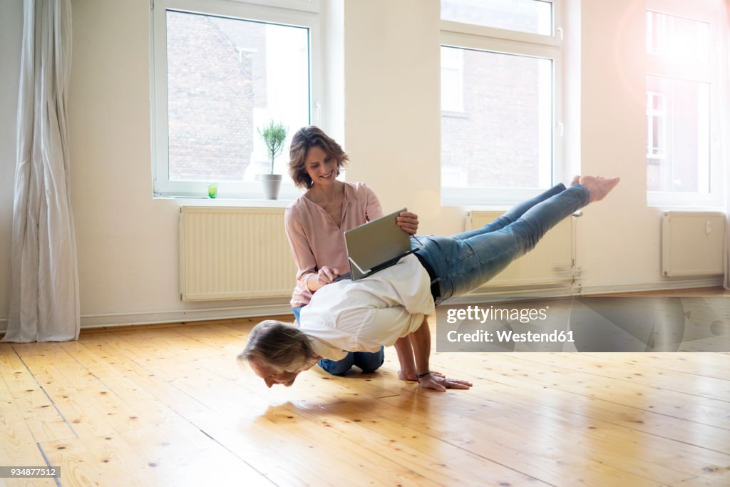 Mature woman using tablet on back of man doing a handstand