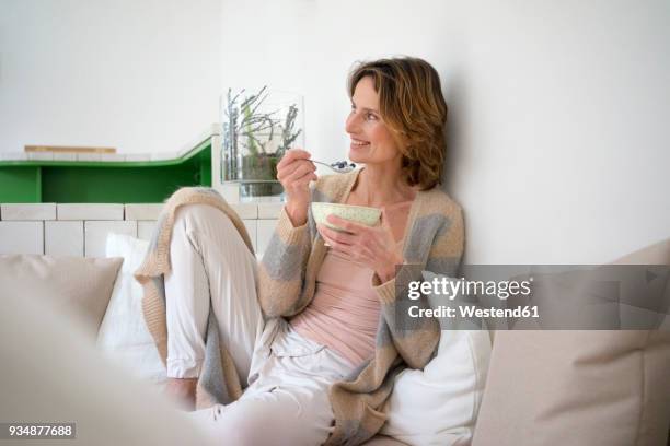 relaxed smiling mature woman sitting on bench eating healthy food - women yogurt stock pictures, royalty-free photos & images