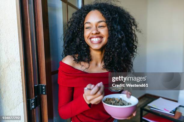 portrait of laughing young woman eating cereals - eating cereal stock pictures, royalty-free photos & images