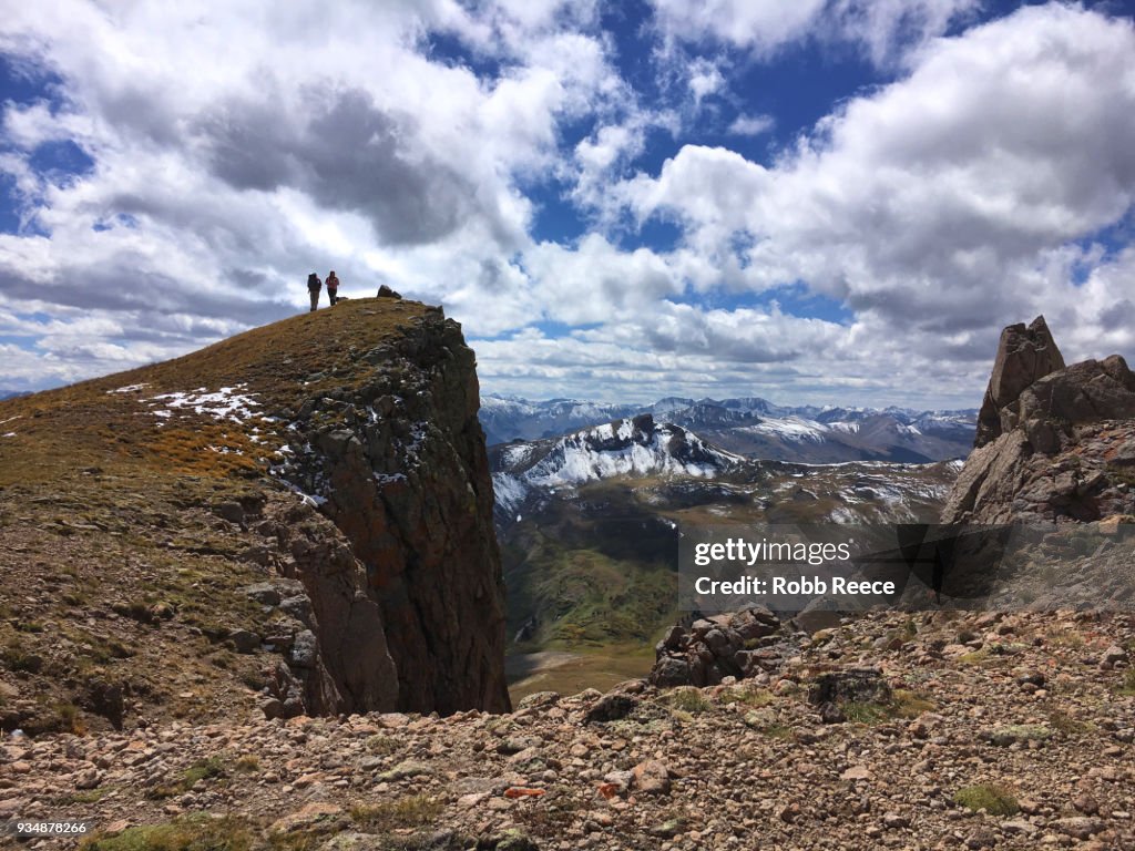 Two people standing on a remote mountain top trail